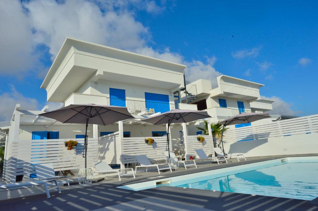 un edificio bianco con sedie e ombrelloni accanto a una piscina di Scala dei Turchi Luxury Home a Realmonte