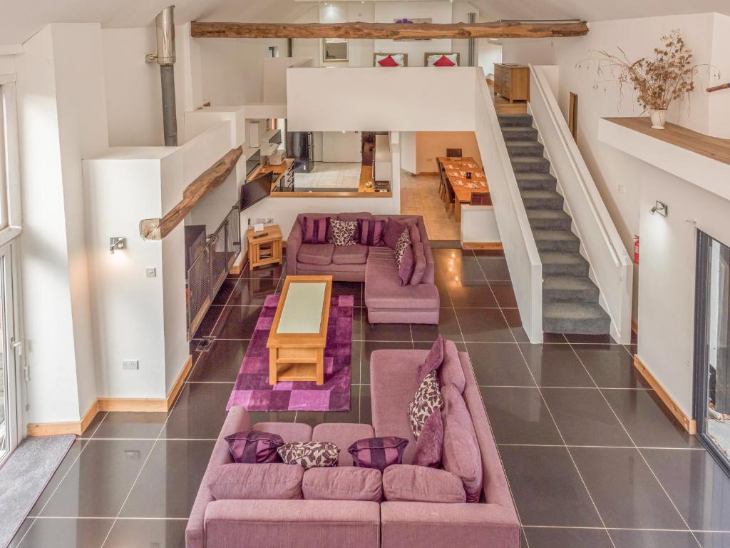 an open living room with purple furniture and a staircase at Flint Barn in North Walsham