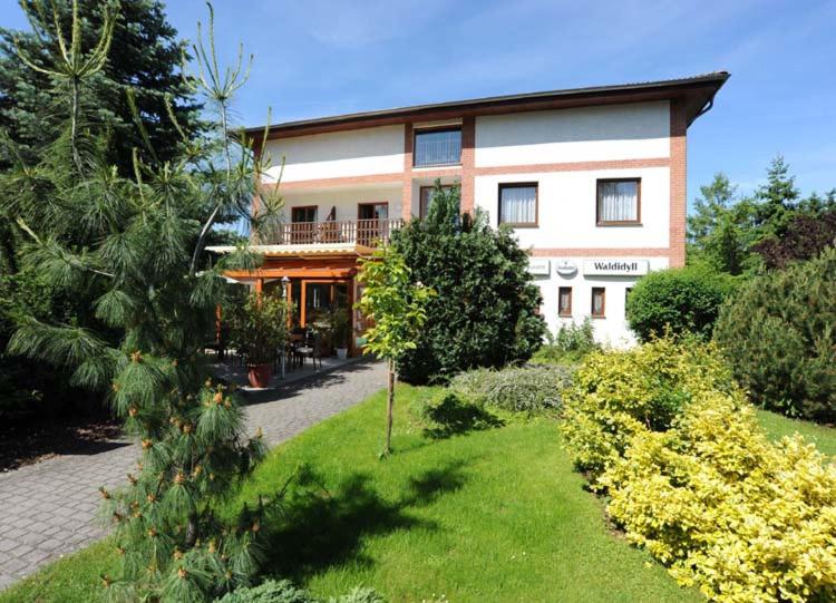 a large house with a garden in front of it at Hotel Waldidyll in Eggesin