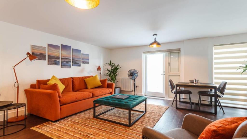 a living room with an orange couch and a table at Stay@Coast in Bournemouth