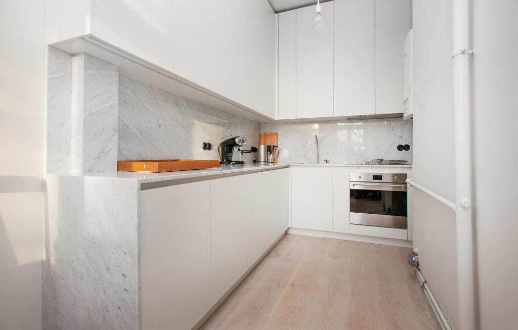 里加的住宿－Ascetic Skolas Street Apartment，白色的厨房配有白色橱柜和木地板