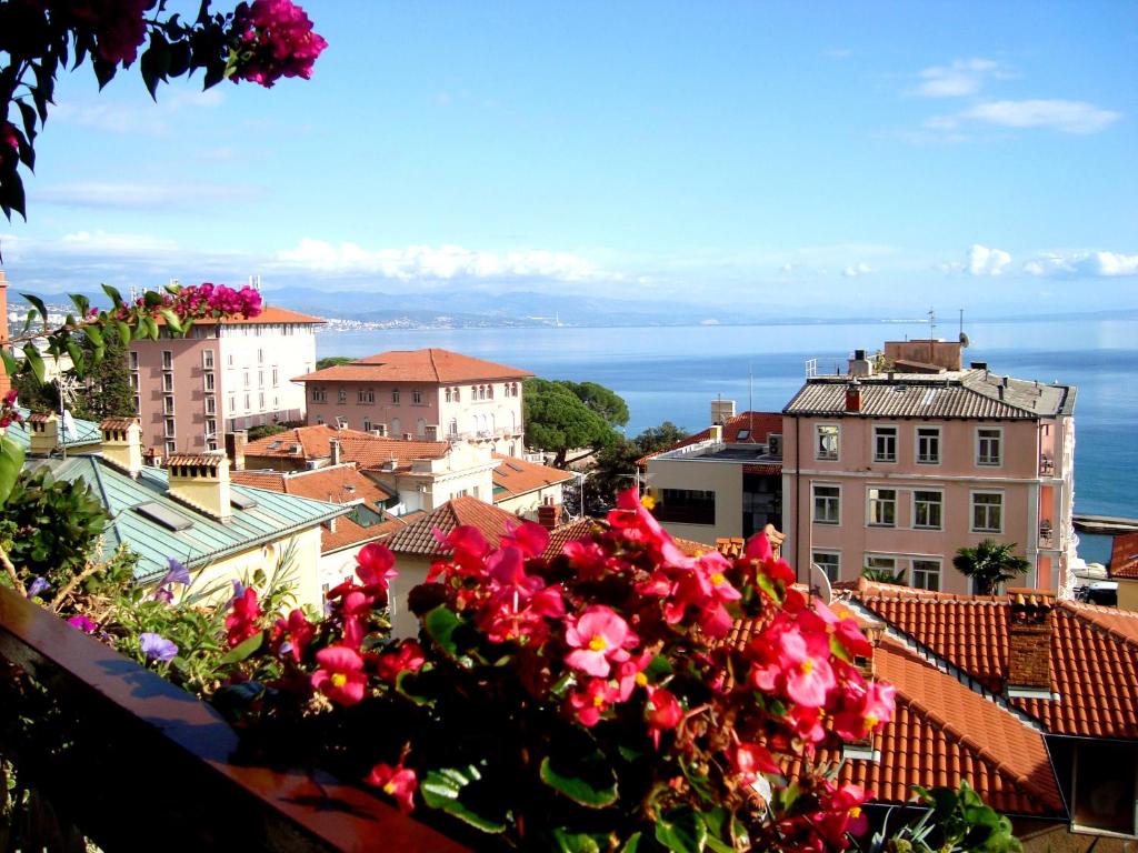 a view of a city with pink flowers on a ledge at Room Malnig Opatija in Opatija