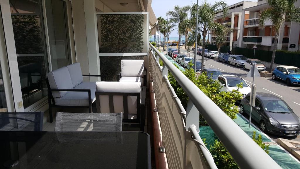 d'un balcon avec des chaises blanches et une rue de la ville. dans l'établissement Appartement 2P et parking privé à 50m des plages., à Villeneuve-Loubet