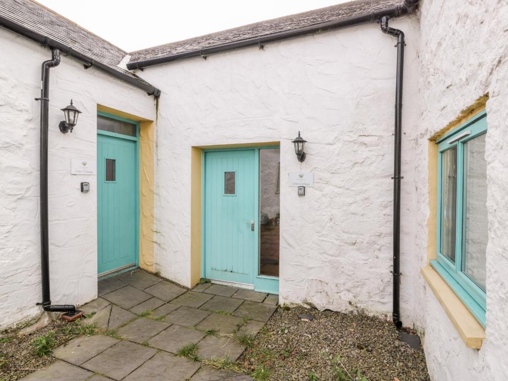a couple of buildings with blue doors on them at Lintie Cottage in Dalbeattie