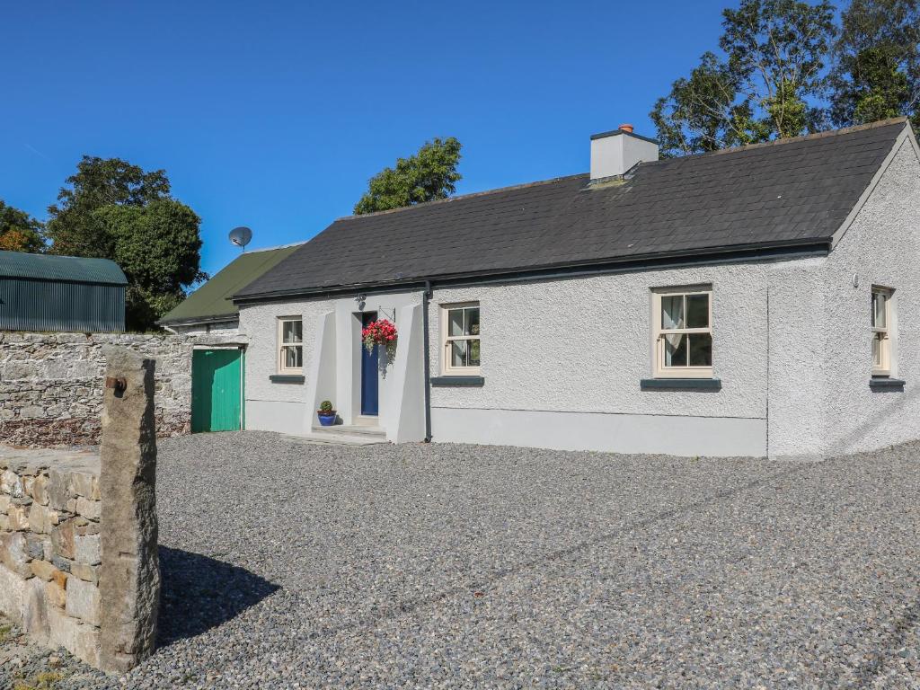 a white house with a gravel driveway at Macreddin Rock Holiday Cottage in Aughrim