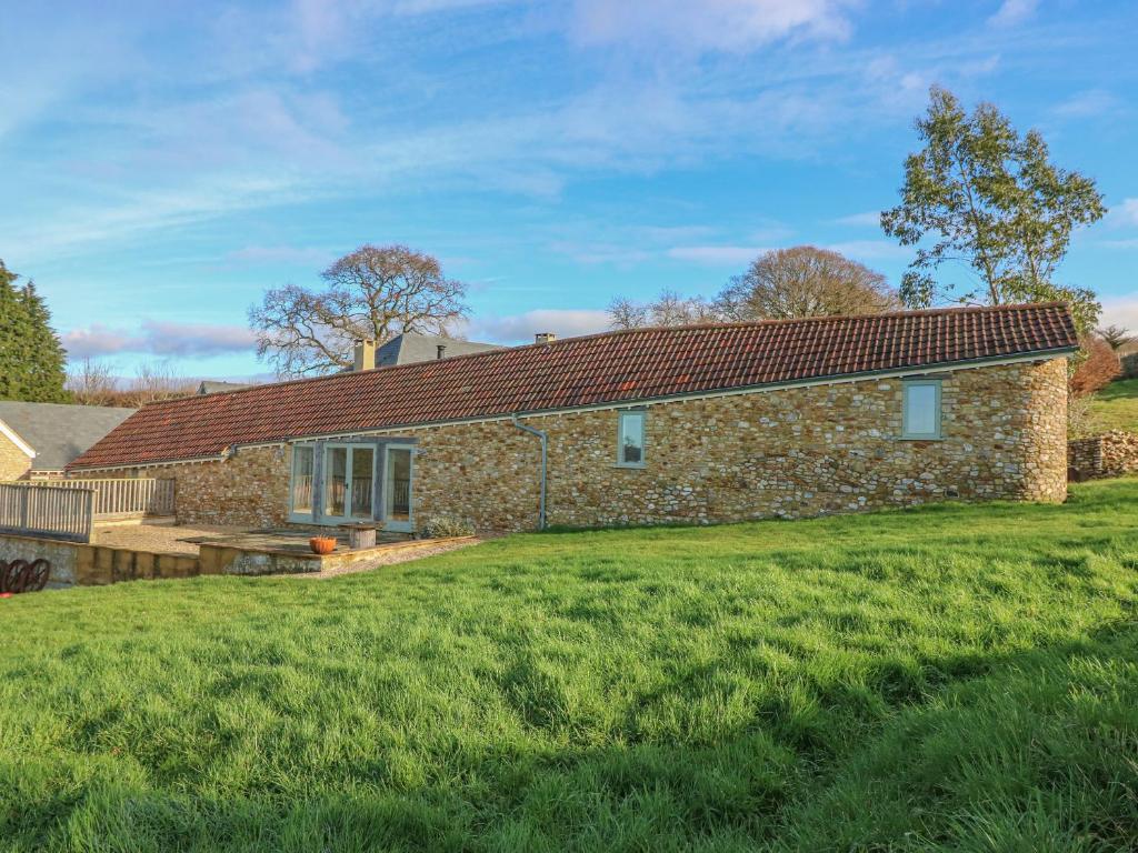 a stone house with a green lawn in front of it at The Shippon in Axminster