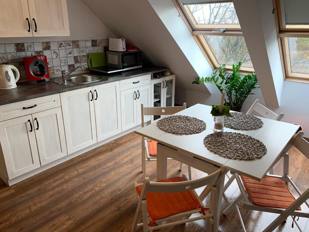 una cocina con armarios blancos y una mesa con sillas. en Sky view Condo in Tarnowskie Góry en Tarnowskie Góry