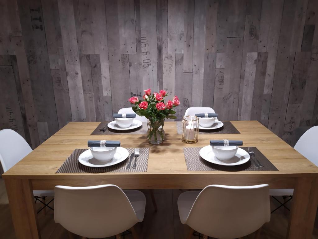 drewniany stół z krzesłami i wazon kwiatów w obiekcie Apartament KAOLA w Jeleniej Górze
