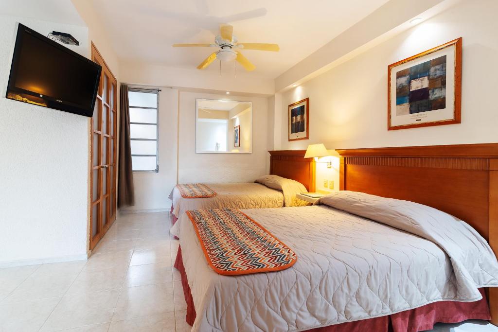 a bedroom with two beds and a flat screen tv at Hotel y Suites Nader in Cancún