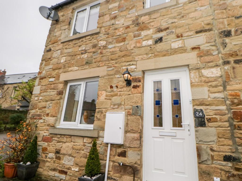 a stone house with a white door and window at Allam Cottage in Barnard Castle