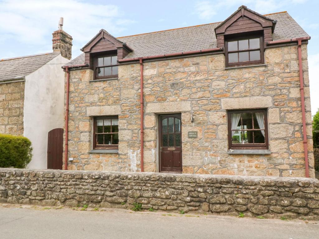 an old stone house with a stone wall at Mossley Cottage in Penzance