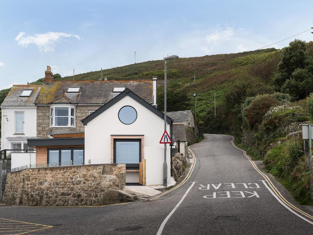 a house on the side of a winding road at The Old Beach Store in Sennen Cove