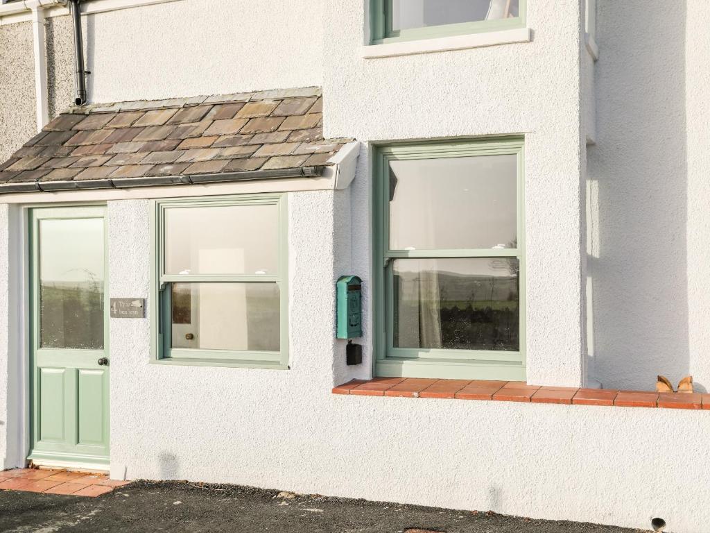 a white house with green doors and windows at Ty ar Ben Bryn in Llanfaelog