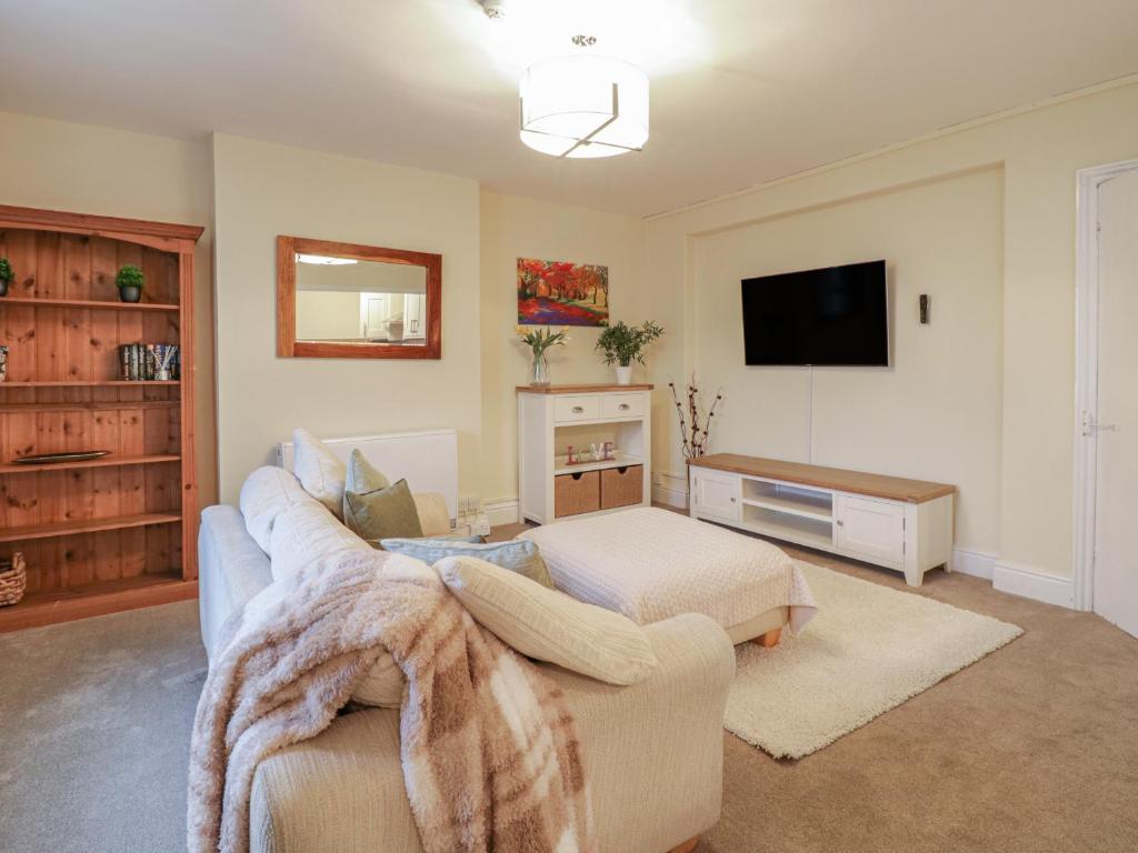 uma sala de estar com um sofá e uma televisão em Beside The Sea - In Town em Llandudno