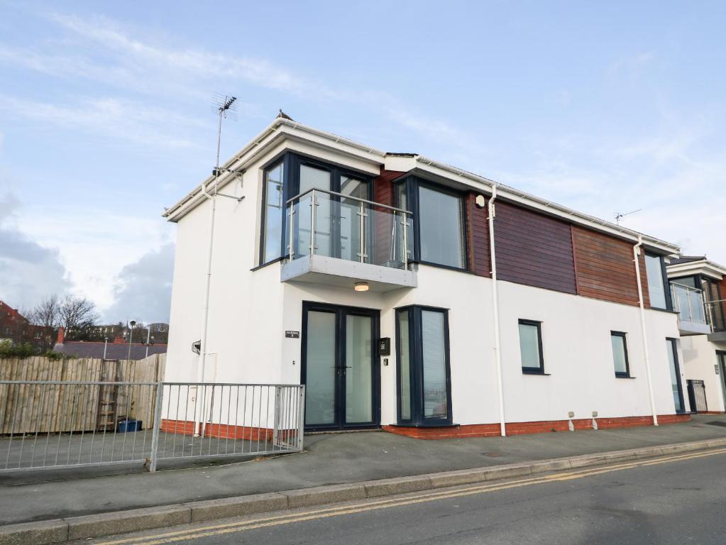 a white house with a balcony on a street at 8 Marina View in Pwllheli