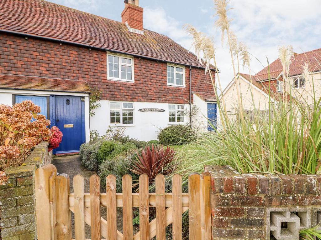 a house with a blue door and a fence at Fisherman's Cottage in Pevensey