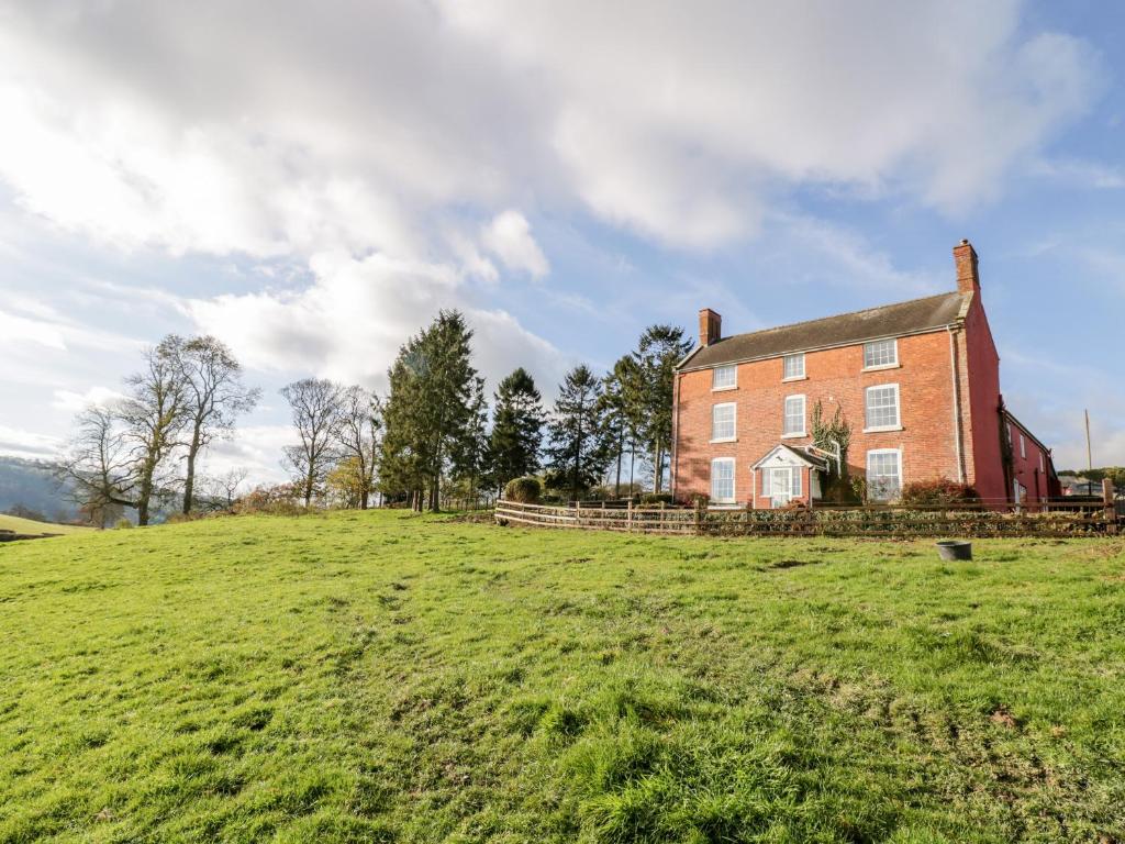 an old red brick house on a green field at Squires Rest in Welshpool