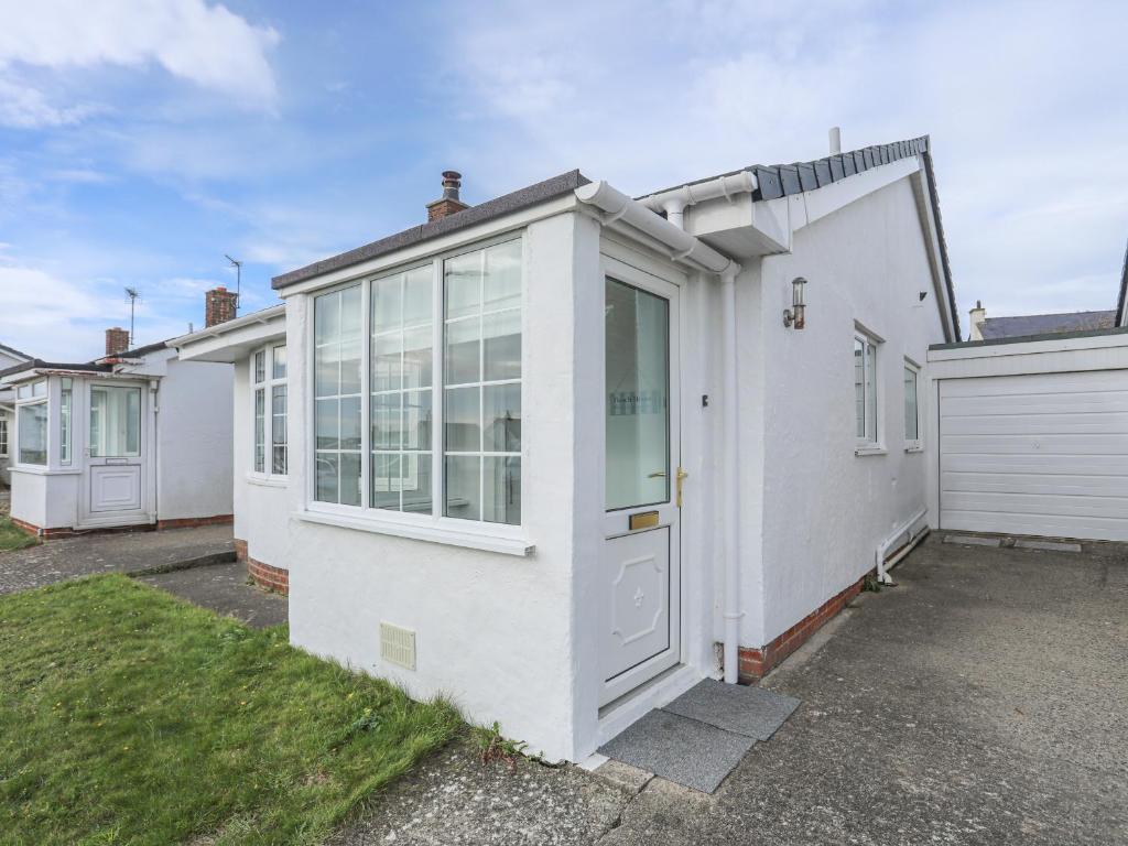 a white house with a door and a garage at Sisial-Y-Mor in Rhosneigr