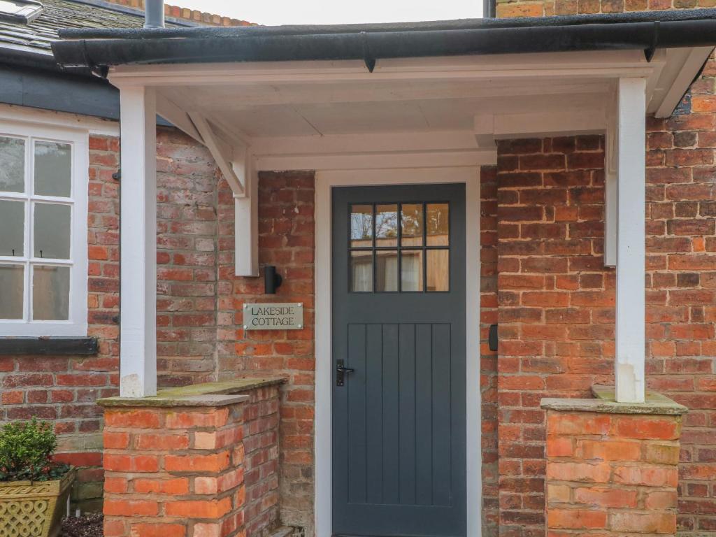 uma porta da frente de uma casa de tijolos com uma porta azul em Lakeside Cottage em Macclesfield