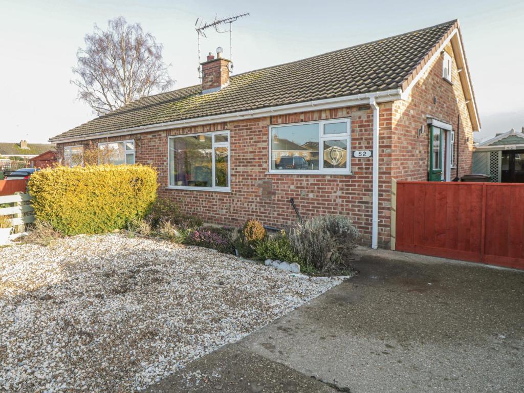 a brick house with a red fence in front of it at The Bungalow at Mill Falls in Great Driffield
