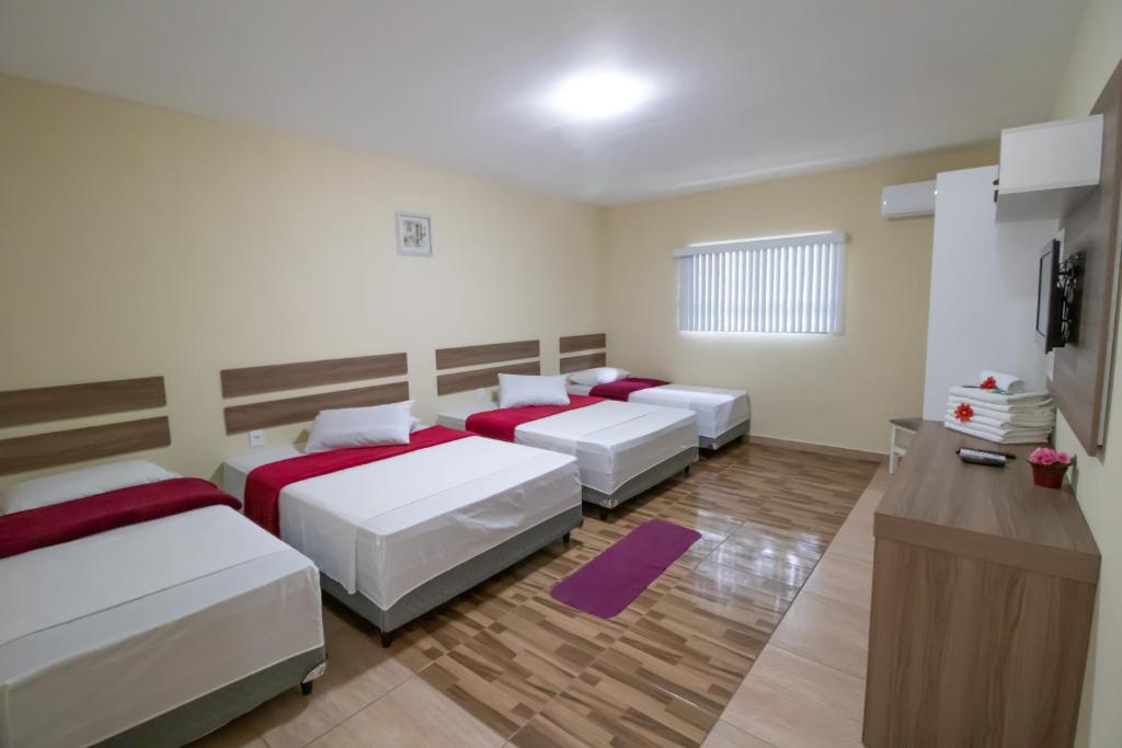 a room with four beds and a tv in it at Pousada Vovó Dilma in Penha