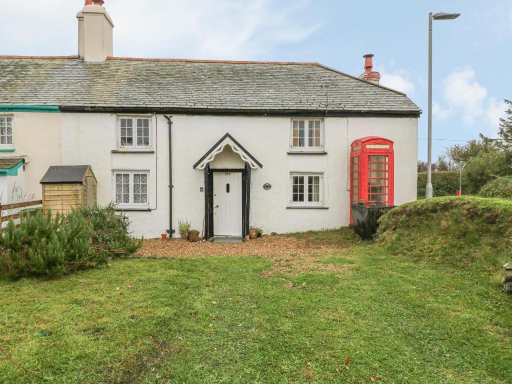 een oud wit huis met een rode telefooncel bij Turnpike Cottage in Bideford