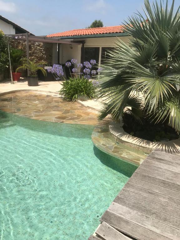 - une piscine avec un palmier à côté d'une maison dans l'établissement T2 entre mer et montagne, à Larressore