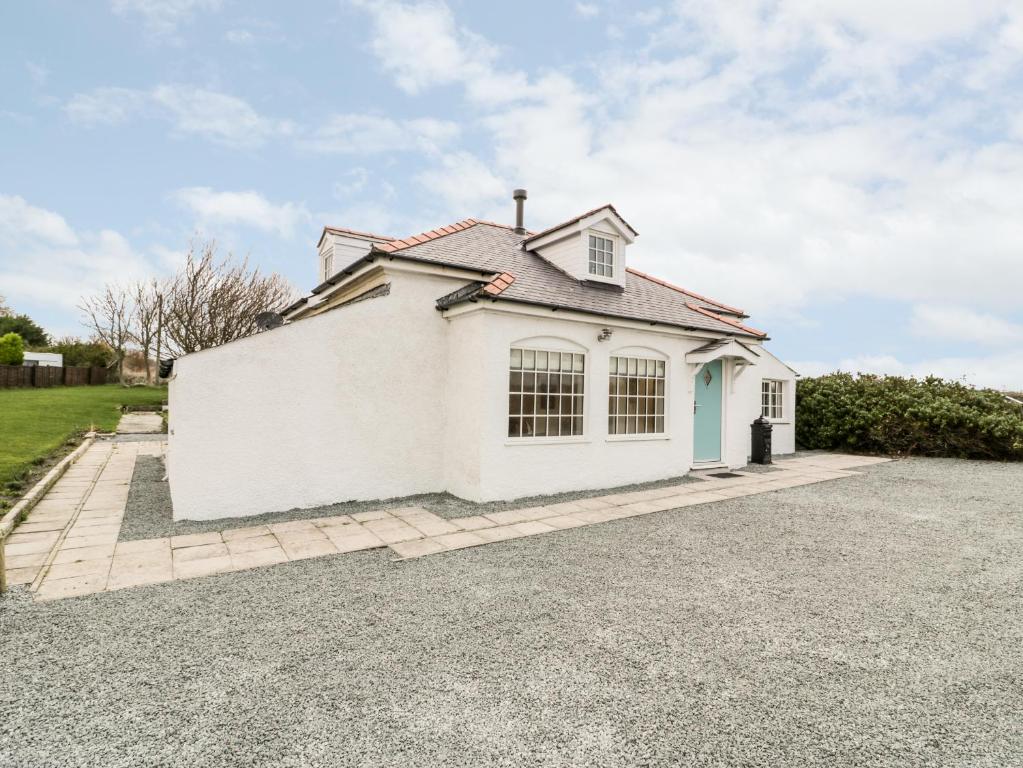 a white house with a gravel driveway at Pentowyn in Holyhead