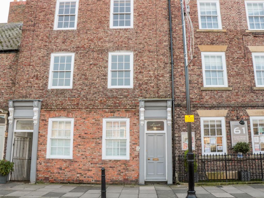 a red brick building with a white door at Tynemouth Village Penthouse in North Shields