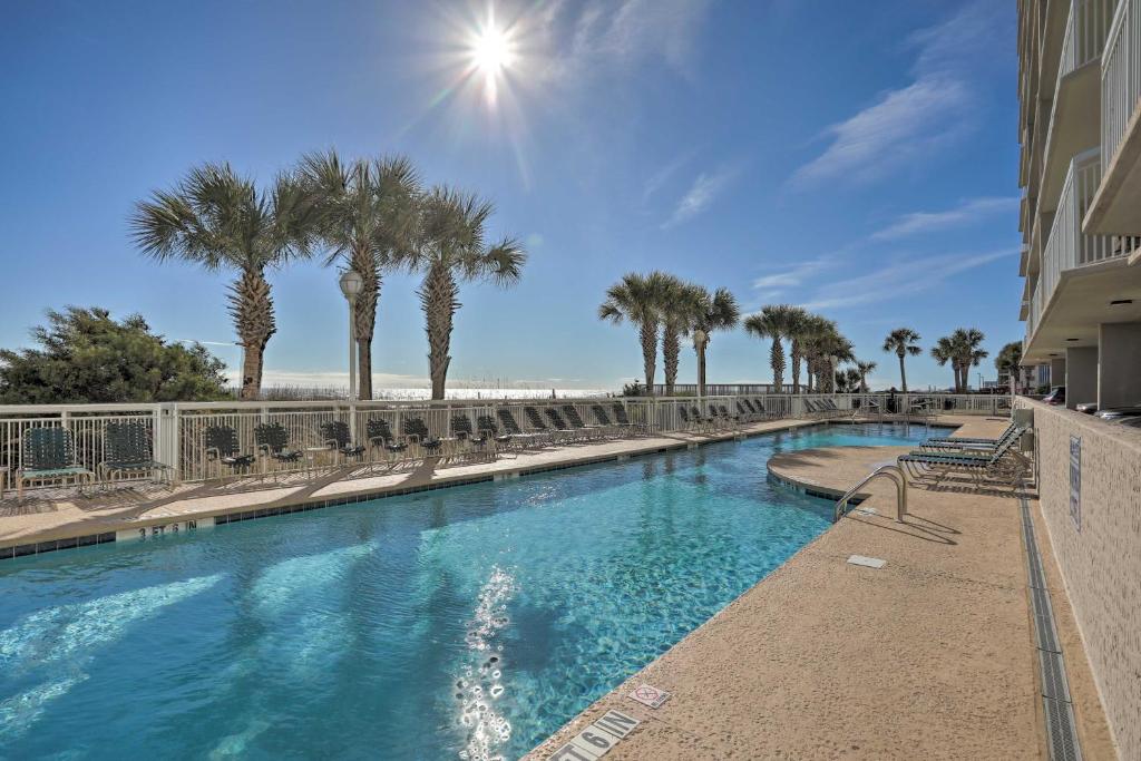 einen Pool mit Stühlen, Palmen und Strand in der Unterkunft Myrtle Beach Seaside Escape with Beach and Pool Access in Myrtle Beach