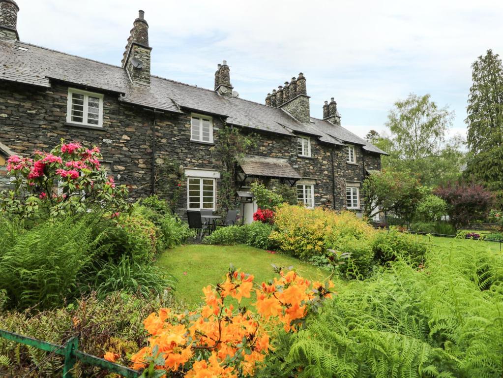 ein altes Steinhaus mit Garten davor in der Unterkunft Ednas Cottage in Ambleside
