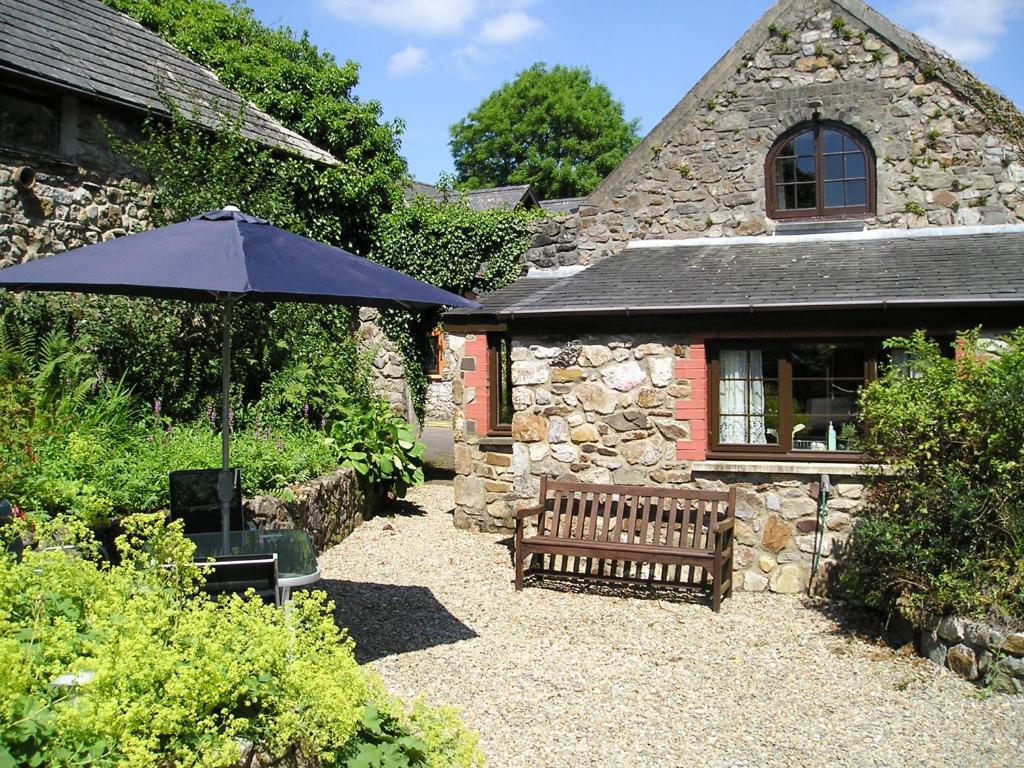 an umbrella and a bench in front of a building at Barn Court Cottage in Narberth