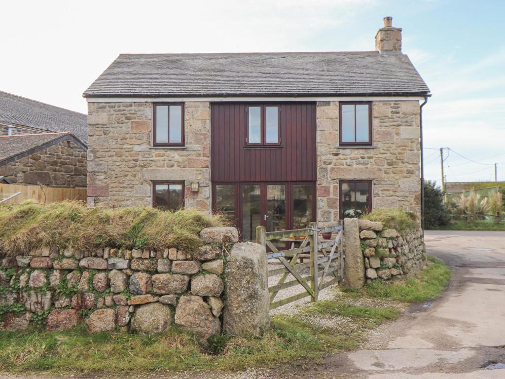 ein altes Steinhaus mit einer Steinmauer in der Unterkunft The Honeypot Cottage in Penzance