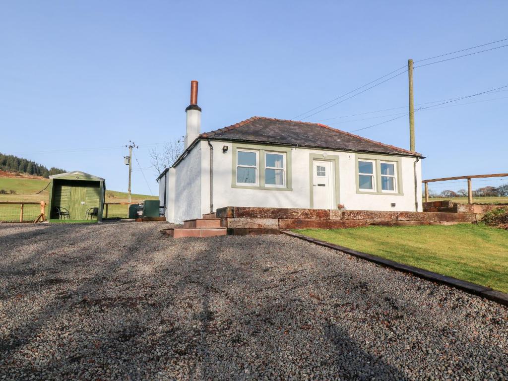 a small white house with a lighthouse on a road at Glebe Cottage in Dumfries