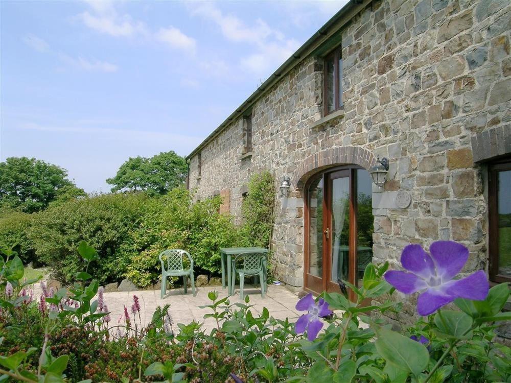 a stone building with a table and chairs in a garden at Stable Cottage in Newport