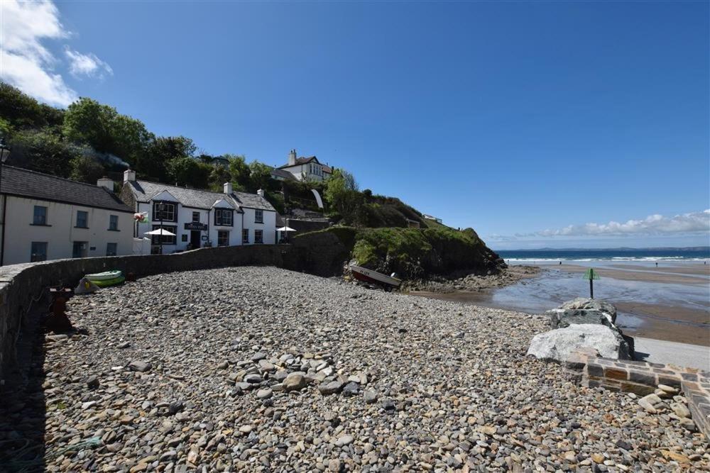 a rocky beach with houses and the ocean at Beach Cottage in Little Haven