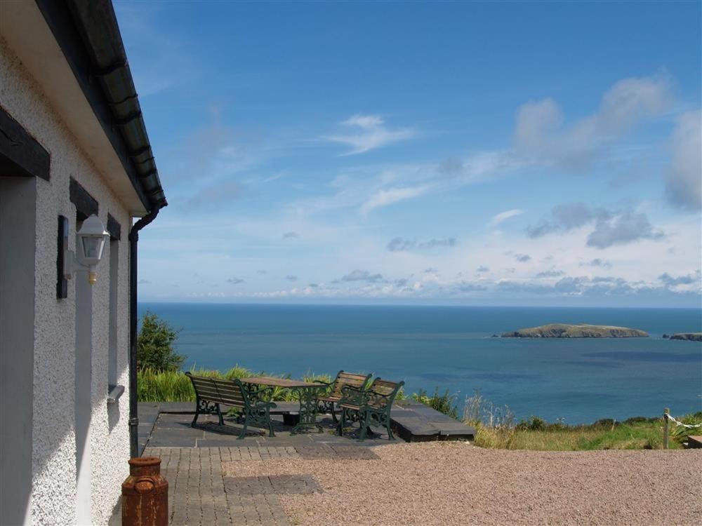 a patio with a table and benches overlooking the ocean at Cockshead Cottage in Saint Dogmaels