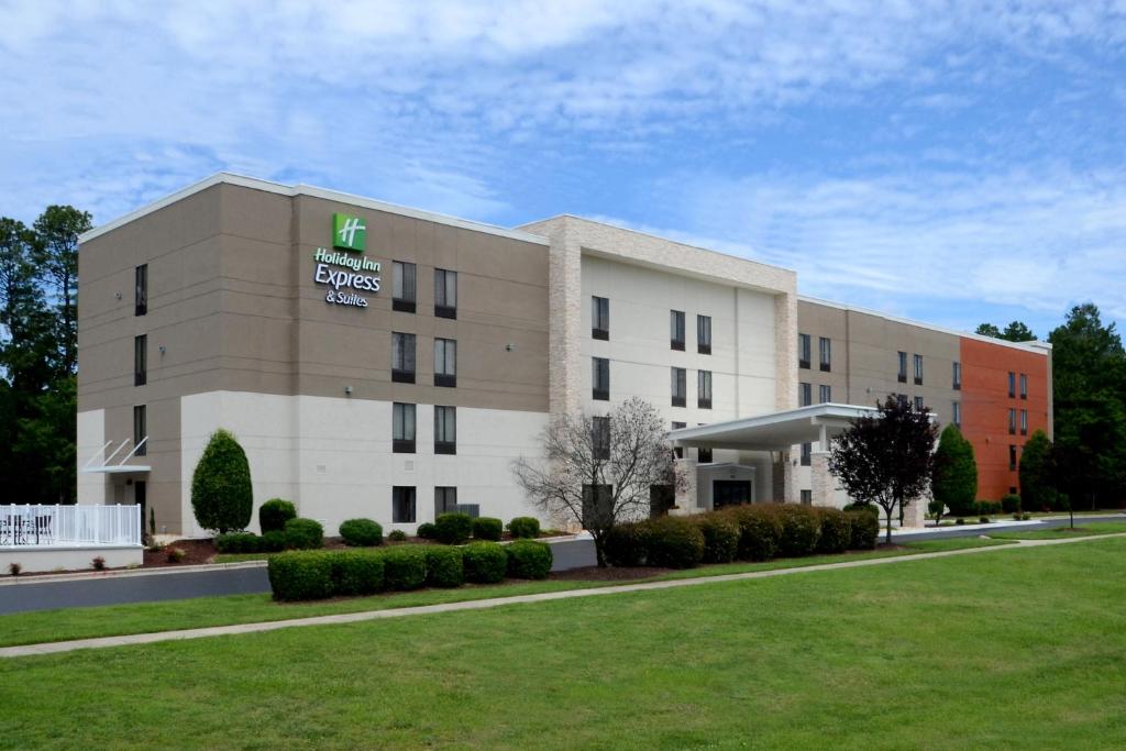 un edificio de hotel con césped delante en Holiday Inn Express & Suites Raleigh Durham Airport at RTP, an IHG Hotel, en Durham