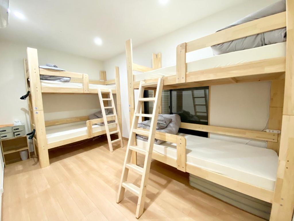 a room with three bunk beds and a ladder at Upper Hotel Ryogoku in Tokyo