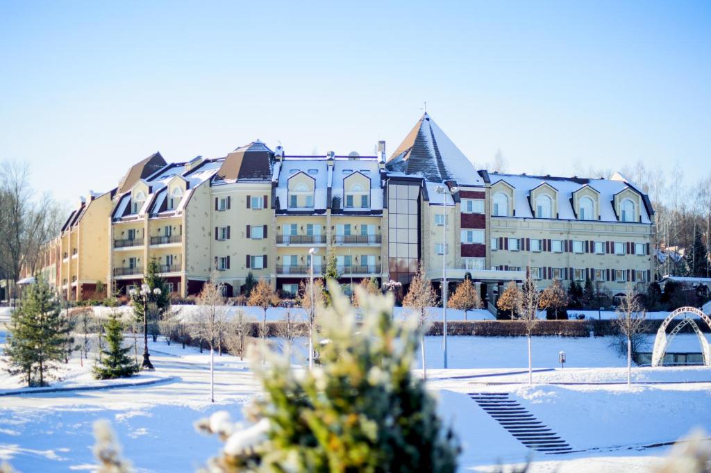 a large building with snow in front of it at Grumant Resort & Spa in Yasnaya Polyana