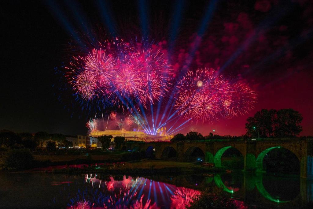 un feu d'artifice au-dessus d'une rivière avec un pont dans l'établissement Hotel du Roi & Spa by SOWELL COLLECTION, à Carcassonne