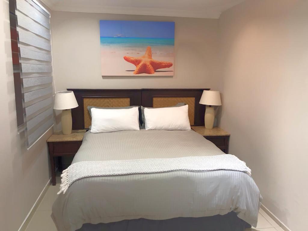een slaapkamer met een bed met 2 lampen en een zeester bij Ballito Backpackers in Ballito