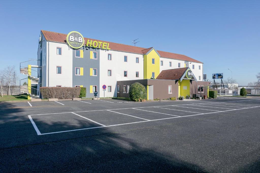 a hotel with a parking lot in front of it at B&B HOTEL Poitiers 1 Futuroscope in Chasseneuil-du-Poitou