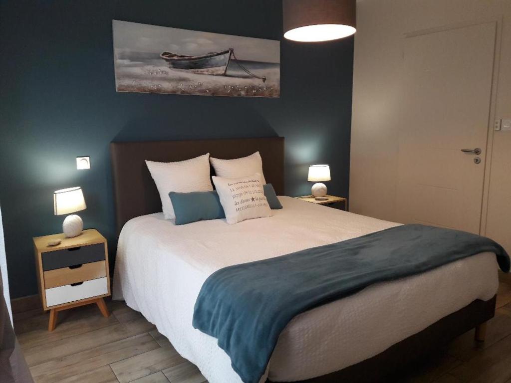 a bedroom with a large bed and two lamps at Le Temps d'une Pause in Bretignolles-sur-Mer