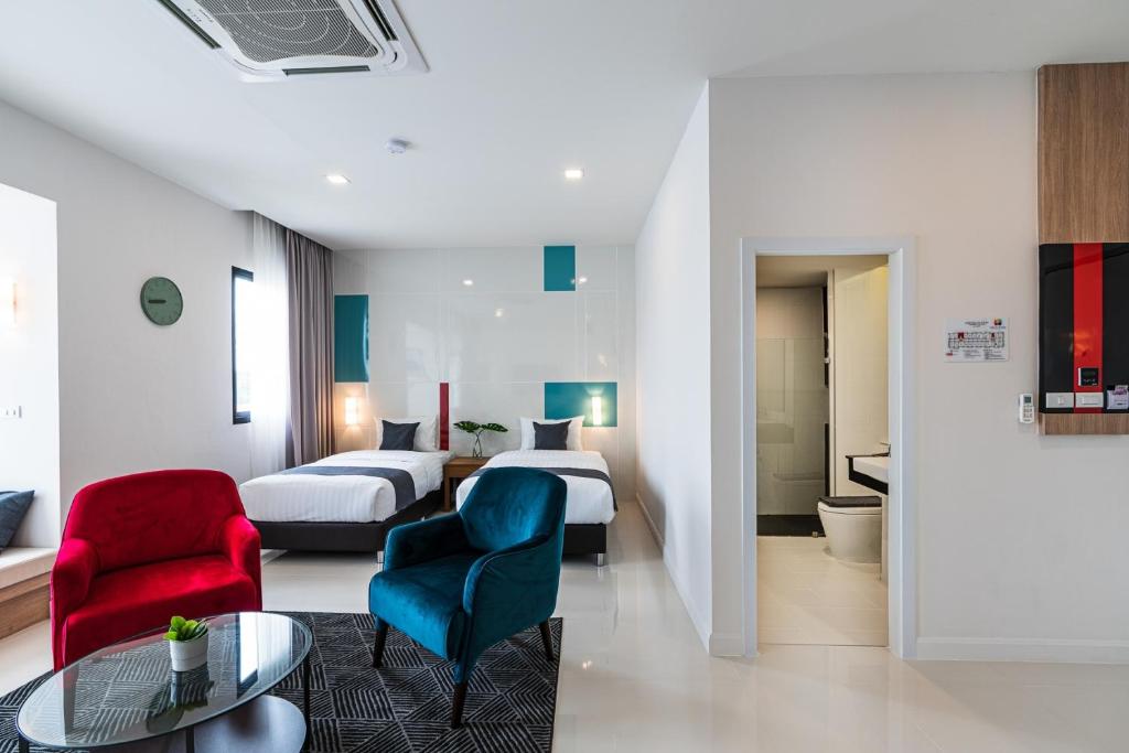 um quarto de hotel com duas camas e uma mesa e cadeiras em The Hi Place em Roi Et