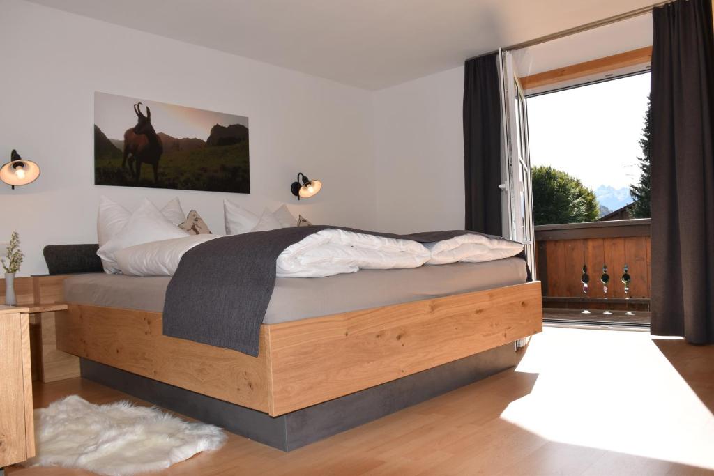 a bedroom with a bed with a large window at FERIENHAUS AM DORFBRUNNEN in Oberstdorf