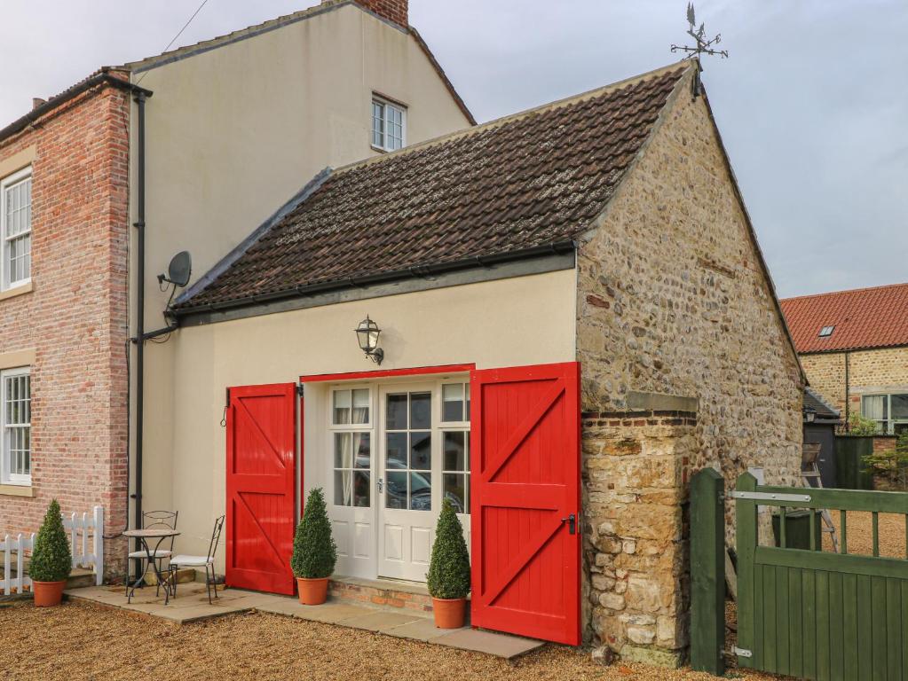 a small house with red doors in front of a building at The Farmhouse Kitchen in Ripon