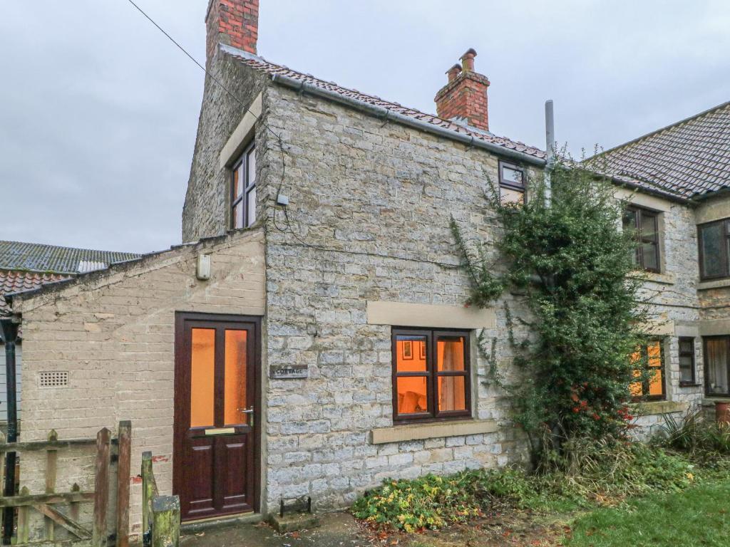 an old stone house with orange doors and a fence at Summerfield Farm Cottage in York