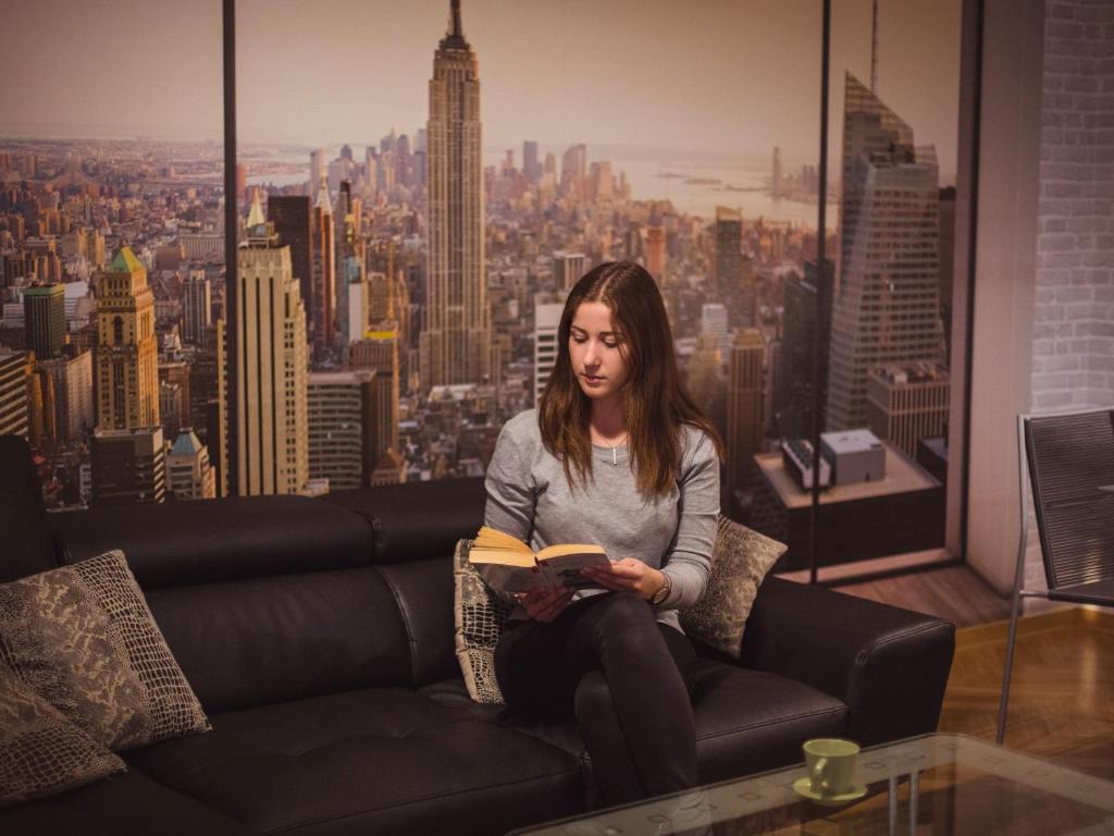 una mujer sentada en un sofá leyendo un libro en Apartment New York, en Mühlhausen