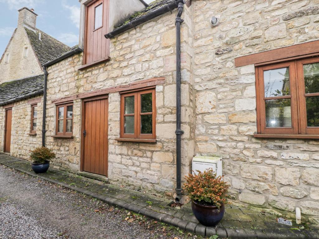 a stone building with windows and potted plants in front of it at Chapel Cottage in Stonehouse